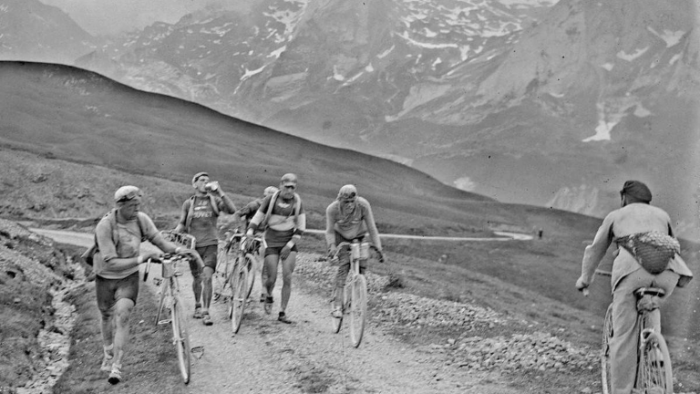Kerékpárosok sétalnak a kerékpárjaik mellett egy hegyi szakaszon az 1925-ös Tour de France során.